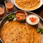 Indian paratha served with chutneys and masala chai, perfect for a hearty meal.