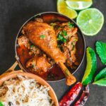 Delicious Indian chicken curry served with basmati rice, garnished with limes and mint leaves.