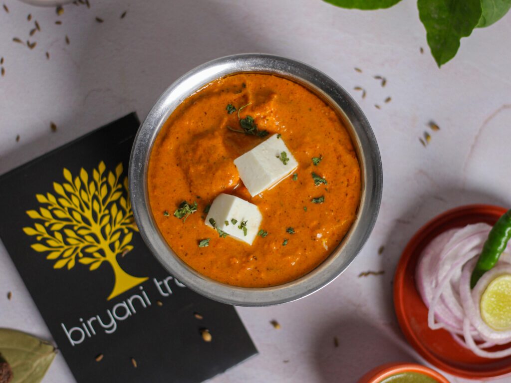 A mouth-watering overhead view of paneer makhani with creamy texture, garnished with herbs.